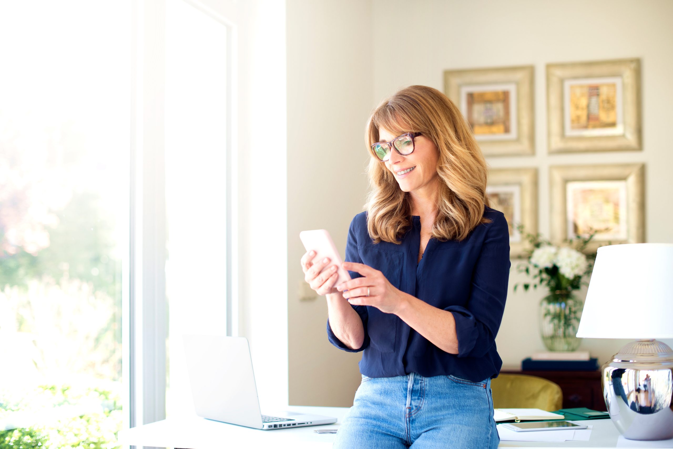 A woman smiling as she scrolls through her mobile device, symbolizing confident engagement with data-driven personalization tools.