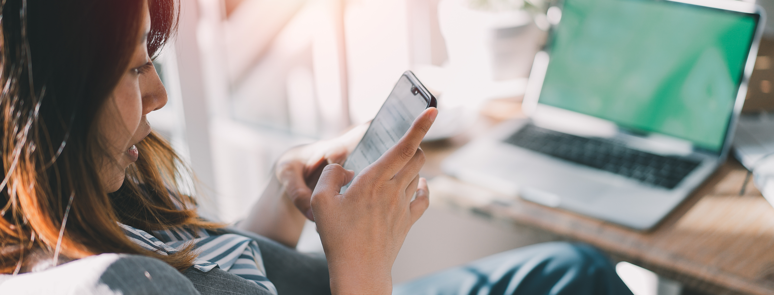A woman looking at her phone, engaging in a text conversation that illustrates effective CRM messaging.