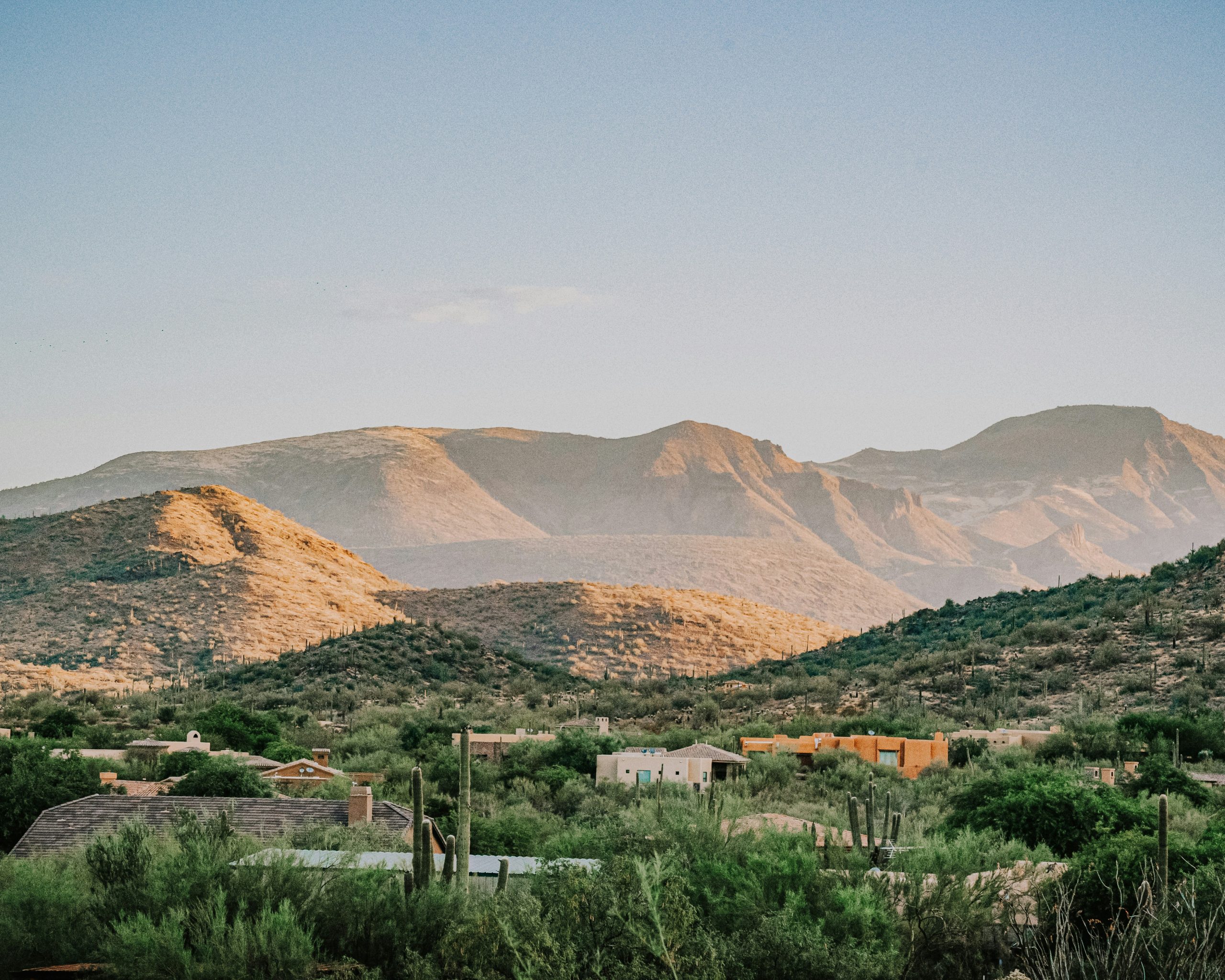 A breathtaking view of Phoenix, Arizona, featuring a vibrant desert landscape with towering cacti, rugged mountains in the distance, and a clear blue sky.